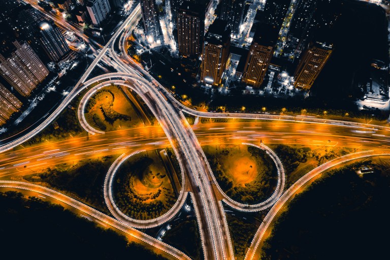 Imagem de estradas iluminadas por postes e carros.